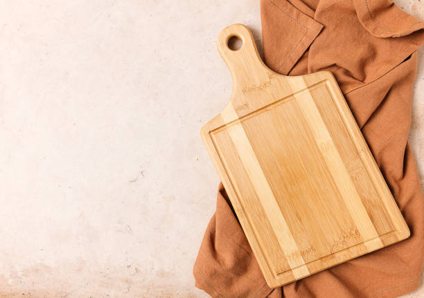 istock Cutting board, beige, unpainted, with a kitchen towel, on a beige background, top view, 1396713468