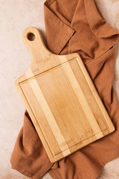 istock Cutting board, beige, unpainted, with a kitchen towel, on a beige background, top view, 1396714237