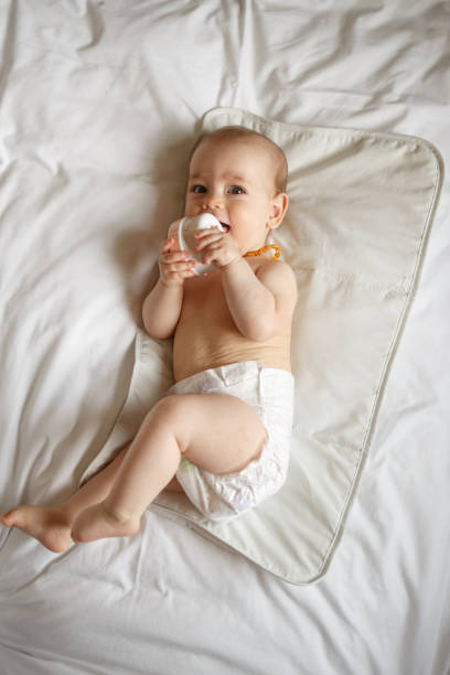 istock Baby girl lying on the bed while wearing only diaper 1396715971