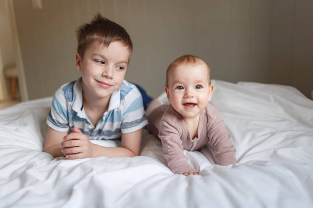 Portrait of a boy and baby girl lying on the bed stock photo