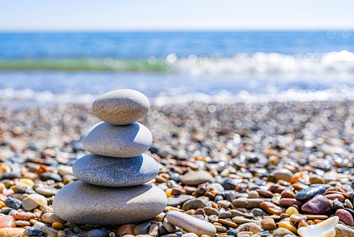 Stack of sea stones with defocused beach at background. High resolution 42Mp outdoors digital capture taken with SONY A7rII and Zeiss Batis 40mm F2.0 CF lens