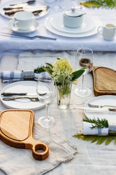 istock Summer holiday table set up. Elegant table setting with white dishes on a white linen tablecloth. Table set for outdoor eating in the garden. Vertical shot 1396716817