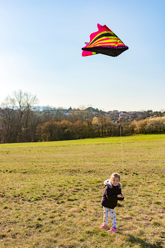 Full length of cute girl playing whit kite in the meadow