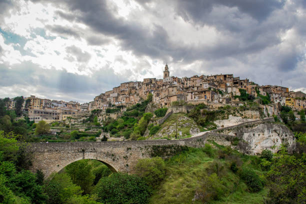 vista geral da bela vila valenciana de bocairent com sua ponte de pedra, suas casas penduradas e sua torre do sino em um dia nublado. conceito de turismo rural na comunidade valenciana - andalusia landscape poble espanyol spanish culture - fotografias e filmes do acervo