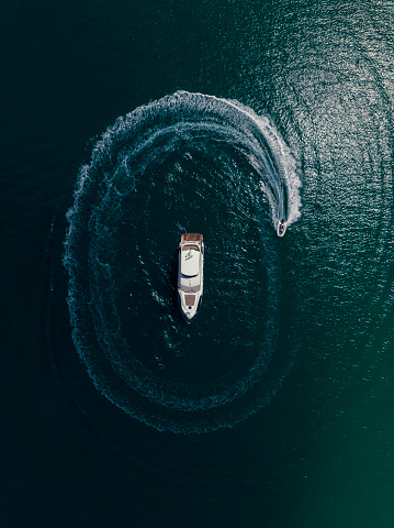 A zodiac boat circling around a  yatcht in  deep waters  of Mediterranean Sea. Taken via drone. Kemer,  Antalya Turkey.