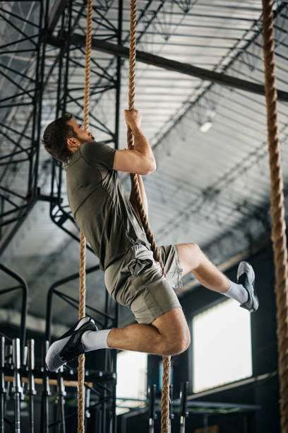 istock Athletic man climbing up the rope during cross training in a gym. 1396727910