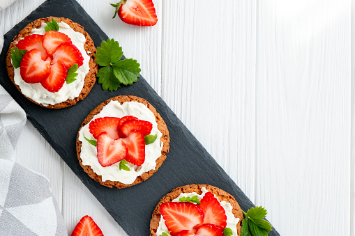 Healthy sandwich with strawberry and cream cheese on slate board. Tasty breakfast. Clean eating, diet or easy recipe of vegetarian sandwich for vegan menu. Flat lay.