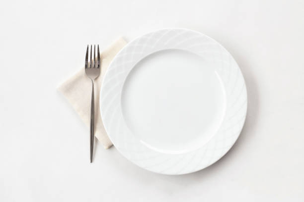 istock Empty white plate with fabric napkin and a fork on white table. Top view. 1396728043