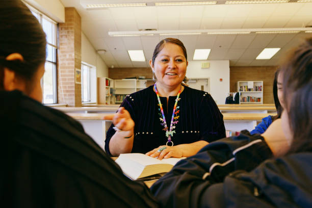 istock High School Teacher and Students in a School Library 1396729832
