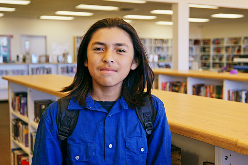 A portrait of an Indigeous Navajo high school student in a school library.