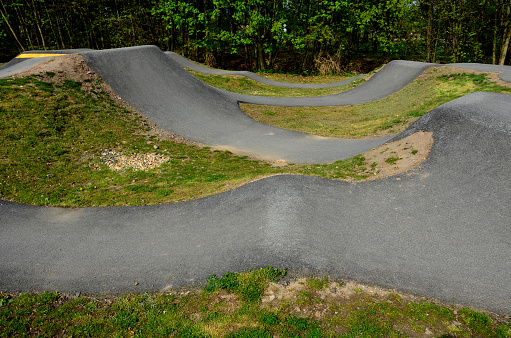 bike path in the car park Pumping (moving up and down) is used instead of pedaling and bouncing to move bicycles, scooters, skateboards and inline skates along the modular pumptrack track