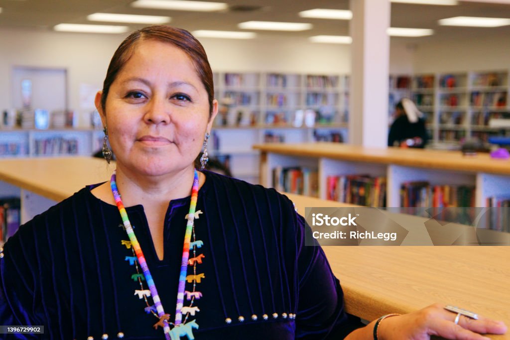 High School Teacher in a Library A portrait of an Indigenous Navajo high school teacher in a school library. Indigenous Peoples of the Americas Stock Photo