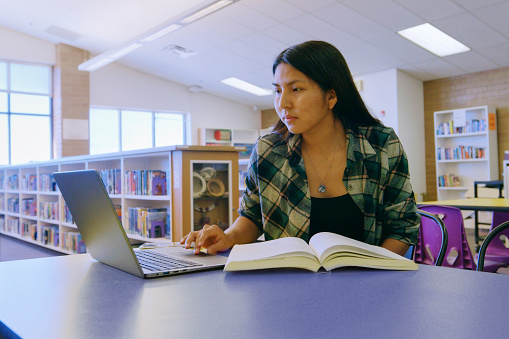 An Indigenous Navajo high school student in a school library.
