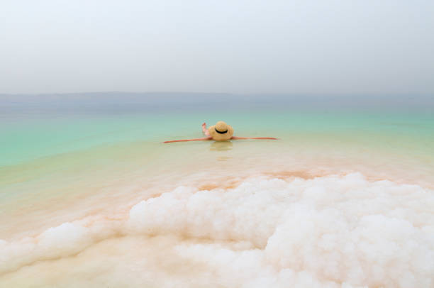 chica con sombrero se relaja y nada en el mar muerto - dead sea fotografías e imágenes de stock