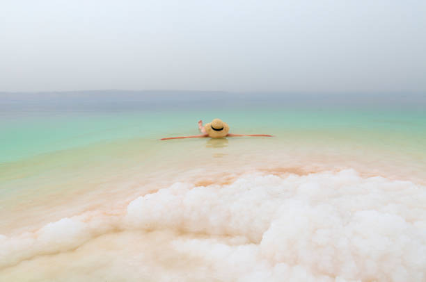 Girl with hat is relaxing and swimming in the Dead Sea stock photo