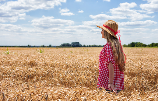 little girl in a hat walking in a field in summer