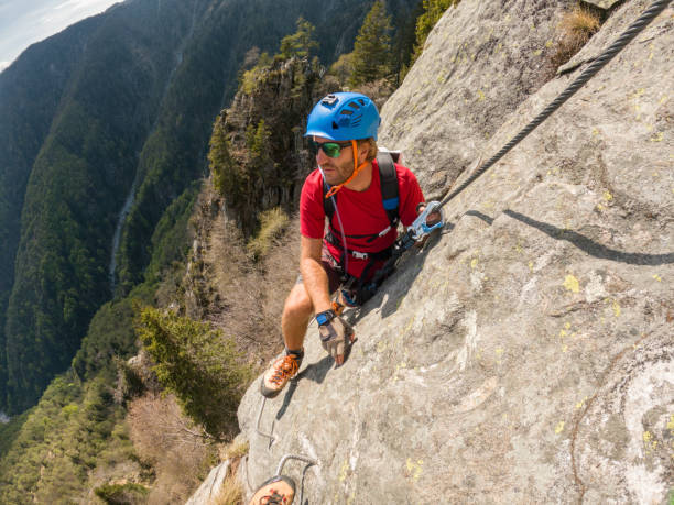 istock Man climbing steep via ferrata on rock cliff 1396741639