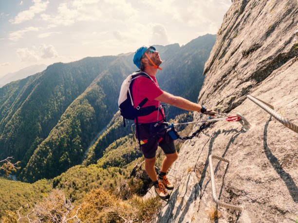 un jeune homme escalade la paroi rocheuse de la via ferrata - european alps mountain mountain peak rock photos et images de collection