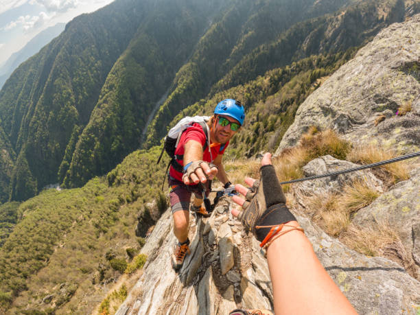 POV down arm to young man climbing up a rock face