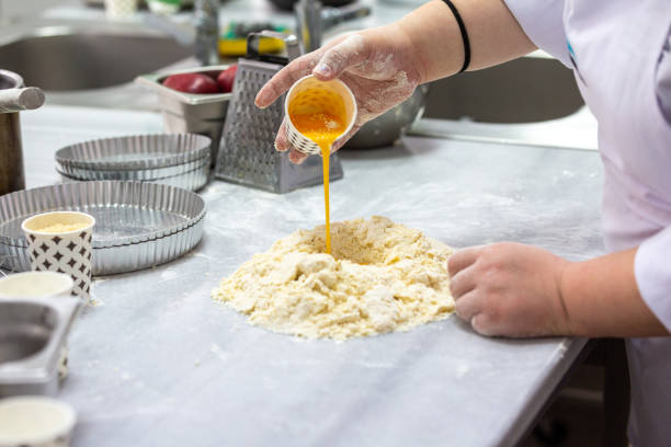 Gastronomic student mixing eggs into dough for apple pie stock photo