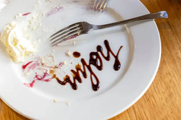 Photo of After the meal Chocolate sign on white plate Enjoy, background with copy space