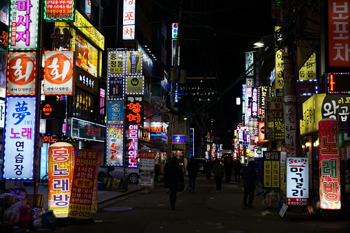 A popular street in the night time in Seoul with lighted advertisment.
