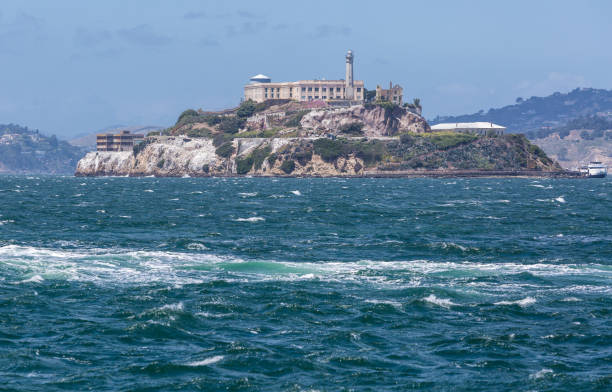 Dramatic image of Alcatraz island in San Francisco Bay with choppy waters in the foreground Image taken from pier 39 San Francisco Bay on a clear windy day. alcatraz island stock pictures, royalty-free photos & images
