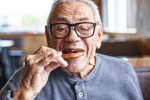 istock Senior Man Eating Toasted Bread With Jelly Jam For Breakfast 1396753271