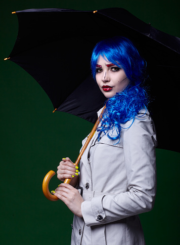 Portrait of young woman in comic  pop art make-up style. Female with umbrella on dark background.