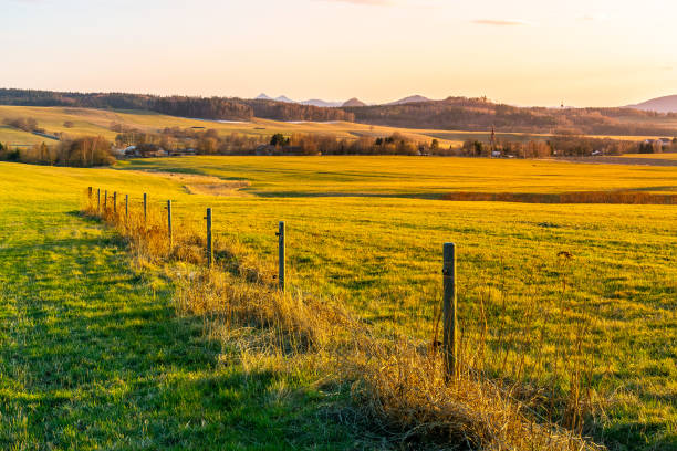 istock Hilly landscape illuminated by evening sunset. Green grass fields and hills on the horizont. Vivid spring rural countryside. Ralsko Mountain, Czech Republic 1396761288