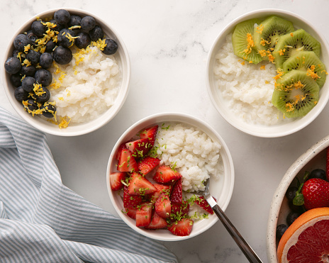 Set of rice porridge with milk in bowl served with strawberry, blueberry and kiwi. Top view.