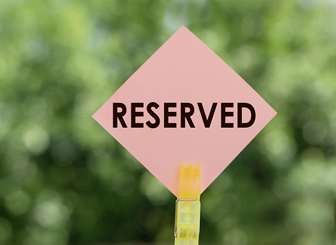 RESERVED - text on pink note paper on green background.