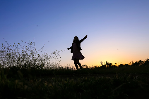 Silhouette of teenage girl at sunset