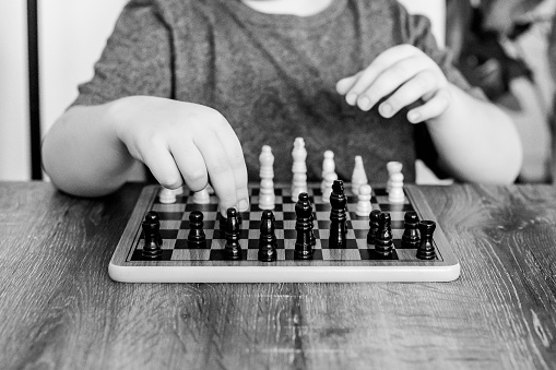 The picture of the child playing chess alone in black and white