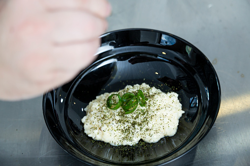 Chef finishing a plate of risotto with herbs