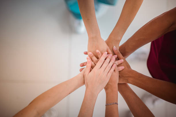 istock High angle view of multiethnic college students stacking hands against with copy space. 1396767562