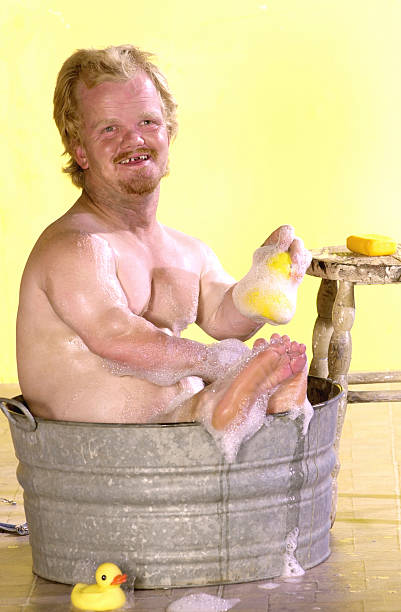 Bath time in a bucket Tiny man takes a bath in a bucket of soapy water with a rubber ducky short stature stock pictures, royalty-free photos & images
