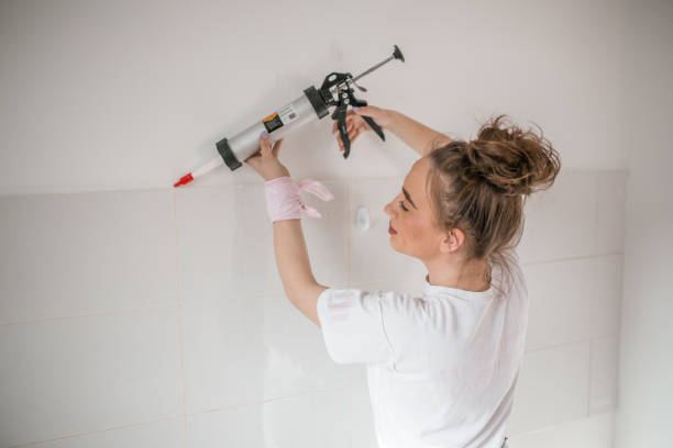 mujer aplicando sellador de silicona con pistola de calafateo en la pared - tile adhesive fotografías e imágenes de stock