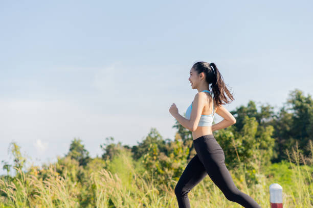 retrato de una mujer asiática haciendo ejercicio al aire libre en un parque, está trotando por buena salud. - running down fotografías e imágenes de stock