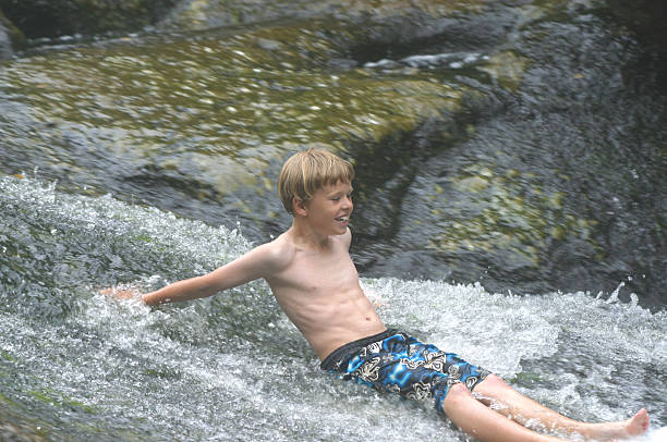 boy racing down stream stock photo