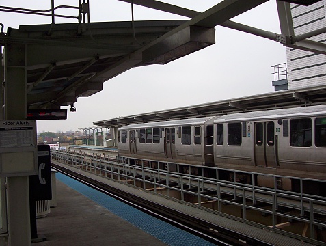 A CTA Elevatated Train is stopped at a station on the Blue Line to discharge and load passengers before continuing to downtown Chicago.