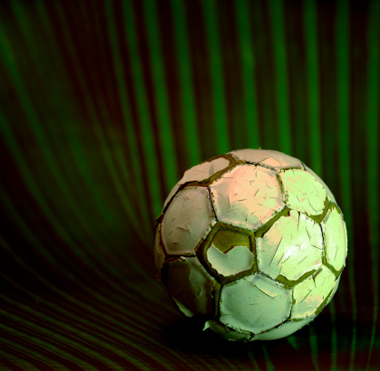 old, battered football with green background