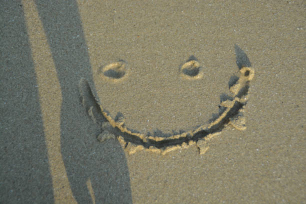 istock A smiley face drawing on a sand. With someone shadow. 1396779262
