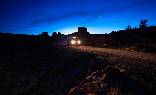 Delivery van driving on a dirt road at night in Moab Utah, USA