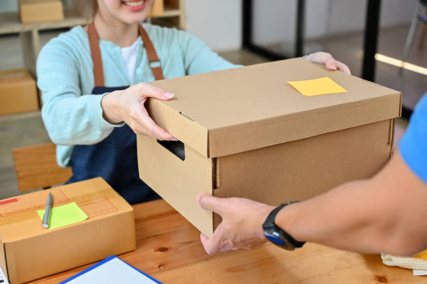 istock Female giving a cardboard box or parcel post box to a delivery man. 1396784525