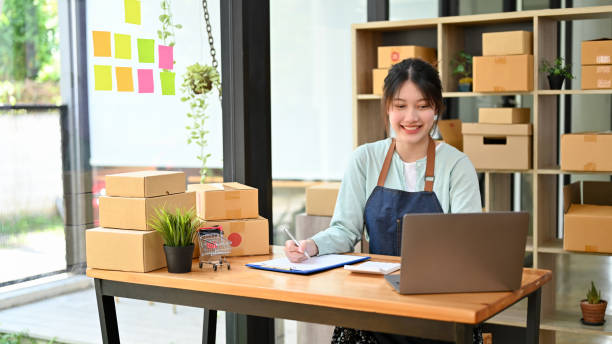 istock Female e-commerce business owner using laptop computer and listing her orders on the clipboard. 1396784640