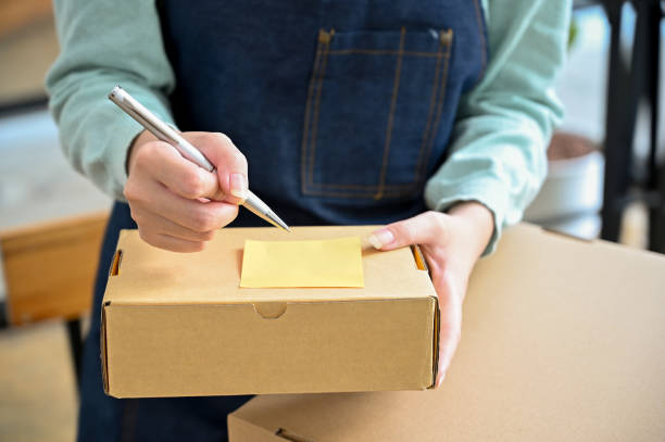 istock Female writing a customer name and address on a small parcel box. Online shopping 1396784840