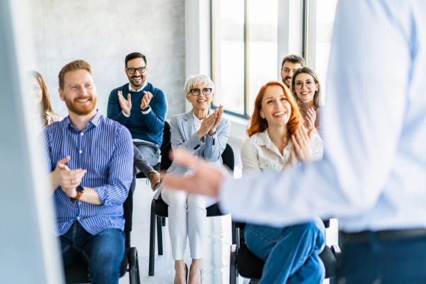 Large group of happy entrepreneurs applauding on a business seminar in the office. stock photo