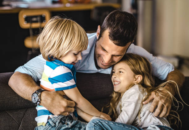istock Happy single father embracing his kids at home. 1396791942