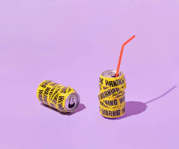 Photo of Summer creative layout with soda cans wrapped in warning packing tape  on pastel purple background. 80s or 90s retro fashion aesthetic drink  concept. Minimal summer idea.